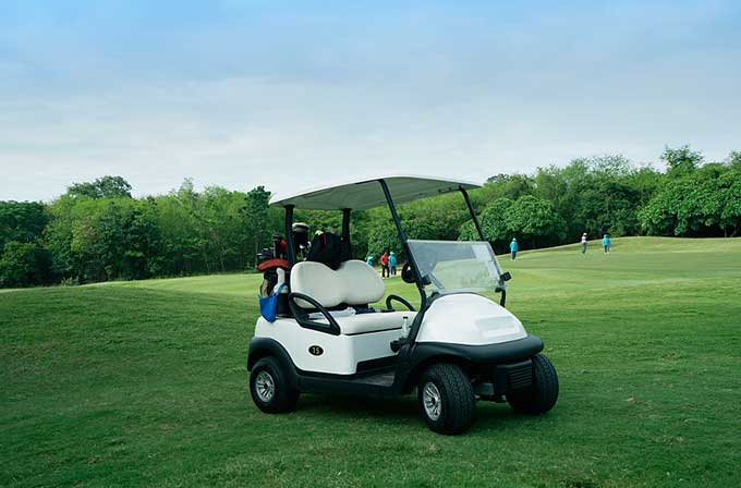 Romantische Kinderwagen auf den Fairways mit elektrisch betriebenen Golf wagen